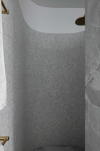A modern marble shower with tiled walls and overhead rainfall shower head.