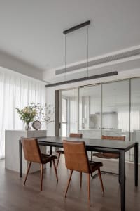 Modern minimalist dining room featuring wood table and leather chairs.