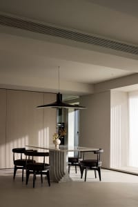 Modern, minimalist dining room featuring a marble table with black chairs and a sleek pendant light.