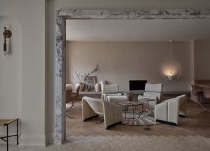 A minimalist living room with concrete walls, white furniture, and natural materials.