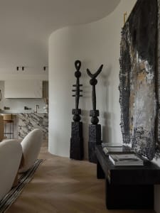 Modern living room interior with black sculptural art pieces, a marble countertop, and minimalist decor