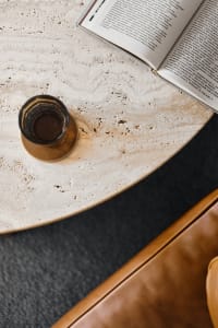 A minimalist interior design featuring a marble table with a book and a drink.