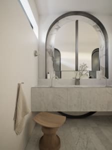 Modern bathroom with marble walls, a floating vanity, and an arched mirror.