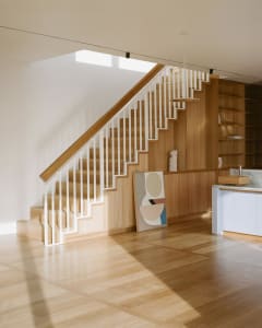Modern interior design featuring wooden flooring and stairs with white railings.