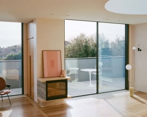 A modern living room featuring glass windows and wooden flooring.