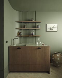 A minimalist bar station with wooden cabinets and shelves holding bottles of whiskey.