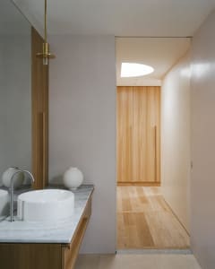 A minimalist bathroom with white porcelain sinks and natural wood elements.