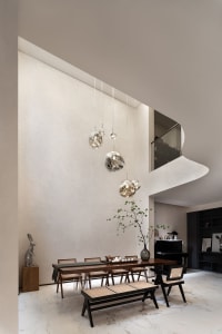 A modern rustic dining room features a wooden dining table, chairs, and bench under elegant spherical pendant lights.