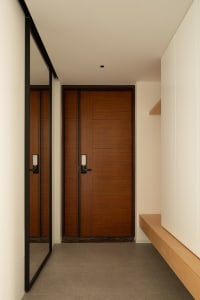 A modern residential entryway featuring a wooden door with sleek, minimalist design elements.