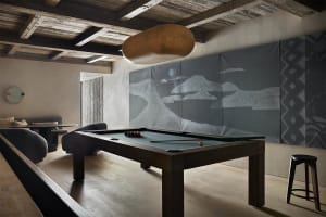 A rustic-style game room featuring a wooden pool table and textured wall art.