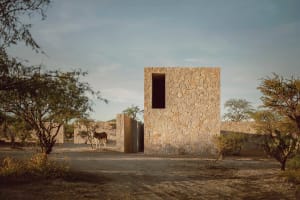 A rustic stone house with a single window in a desert landscape.