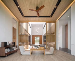 A minimalist living room featuring white walls, wooden paneling, and a low coffee table with a cat on it.