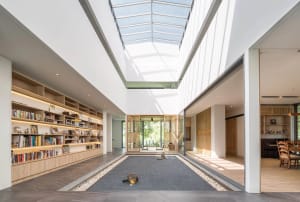 A modern residential interior featuring minimalist decor, wooden elements, glass walls, and stone flooring.