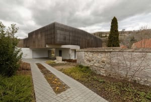 Modern residential building with wooden exterior panels and a stone pathway.