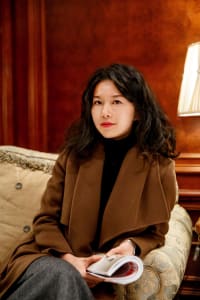 A woman sitting on a wool couch in a cozy living room.