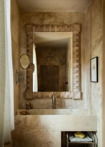 A modern bathroom featuring a stone countertop with a rectangular mirror and metallic fixtures.