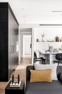 Modern, minimalist residential interior featuring white marble countertops and black wood cabinetry.