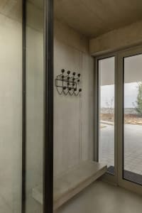 Modern minimalist entryway featuring concrete materials with a unique black coat hanger