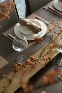 A well-set dining table with modern decor, including gold accents and a wooden centerpiece.