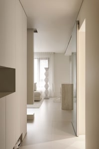A minimalist white interior space with a light-colored geometric vase and a white sofa.