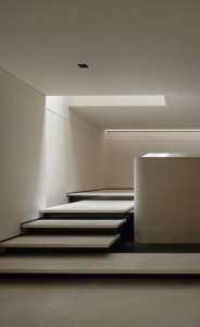 Modern staircase with concrete steps and white walls.