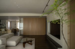 A modern living room with a wooden panel wall and a glass coffee table.