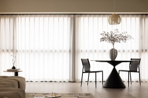 A modern minimalist living and dining room featuring a fabric curtain, round table, and chairs.