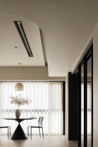 A minimalist modern residential living space featuring transparent textiles and dark wooden accents.