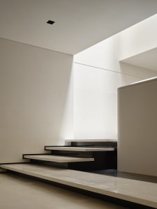 Modern interior space with minimalist design, featuring a minimalist staircase with white marble steps and black marble rails