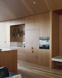 A minimalist kitchen featuring wooden cabinets and flooring.