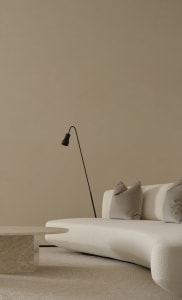 Modern interior design featuring a white curved sofa, a circular table, and a minimalist floor lamp.