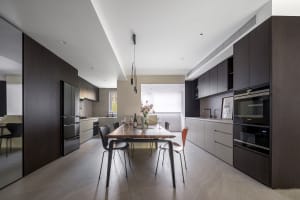 Modern kitchen with wooden countertops and table, featuring stainless steel appliances and a large window.