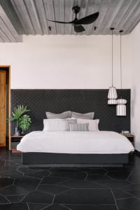 A modern bedroom with a concrete ceiling, glass fronted nightstands, and a floating bed.