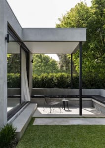 Modern minimalist patio area with concrete seating and black metal frame furniture