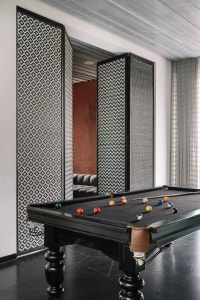 An industrial-style pool room with a black concrete floor, a pool table with billiard balls, and decorative floor-to-ceiling 