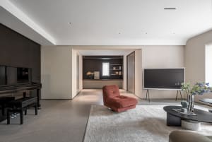 A modern living room with concrete flooring, minimalist decor, and a single red plush chair.
