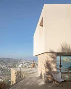 A modern residential building with a concrete exterior featuring large windows and a minimalist design.