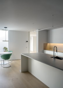 Modern minimalist kitchen featuring concrete countertops and wood flooring.