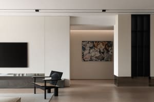 Modern minimalist living room featuring sleek wooden furniture with a marble top, a glass wall, and abstract artwork.