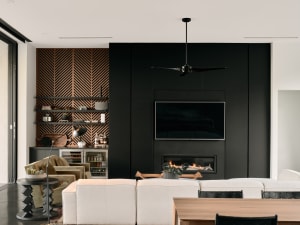 Modern living room with black walls and metal paneling, featuring a white sectional sofa, wooden coffee table, and black ceil
