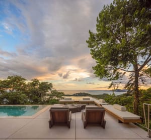 Modern patio with concrete swimming pool, lounge chairs, and scenic ocean view.