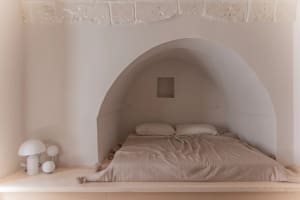A minimalist bedroom with a concrete wall and built-in bed.