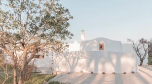 Minimalist white plaster exterior home with tree shadows cast on the wall.
