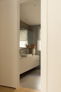 Modern bathroom with neutral tones, featuring a sleek white vanity and minimalist design.