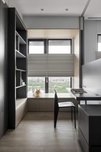 A modern home office featuring a wooden desk with a view of the cityscape outside the window.