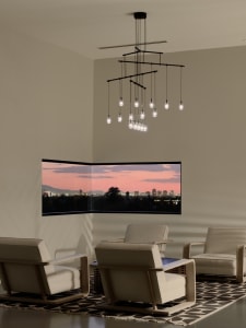 A modern living room with textured paint walls, minimalist furniture, and a large window overlooking a cityscape at sunset.