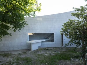 Modern residential home made of concrete with large windows and outdoor area.