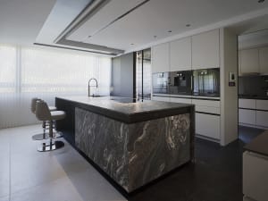 Modern residential kitchen with a marble island and black and white flooring.