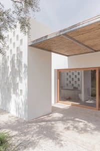 Modern minimalist exterior architecture with concrete walls and a wooden roof structure.