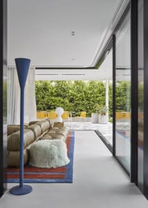 Modern living room with a concrete floor, glass sliding doors, and a green fur blanket.